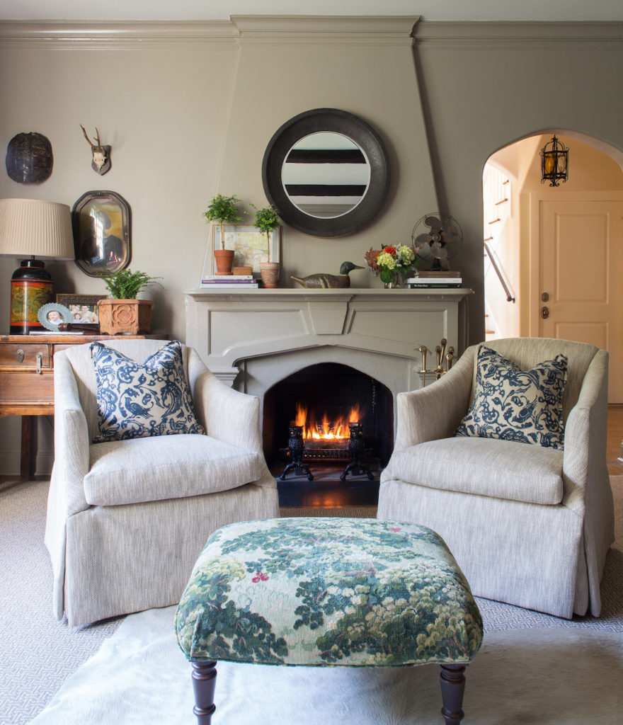 This cozy library just makes you want to grab a cocktail and have a seat. The layering of textures and centering of chairs and ottoman on the fireplace create warmth and ground the room.
